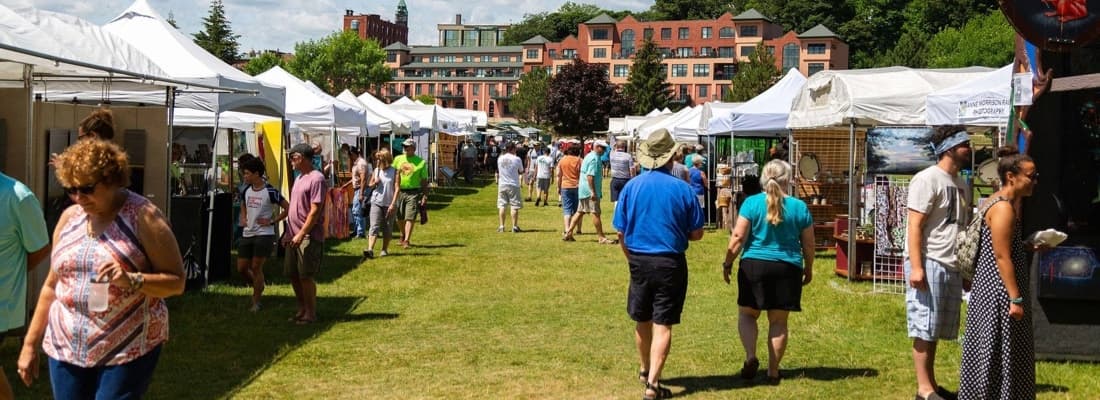 Visitors browsing artist tents at Art on the Rocks in downtown Marquette